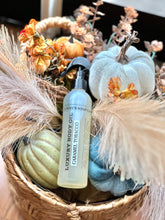 Load image into Gallery viewer, Caramel Tobacco luxury body oil displayed in a fall basket with pumpkins and flowers.