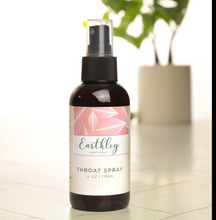 Load image into Gallery viewer, Bottle of Earthly Wellness throat spray on a light surface with a plant in the background