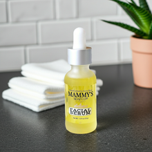 Load image into Gallery viewer, Bottle of Mammy's Soap Co. facial serum on a bathroom counter with towels and a plant in the background.