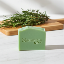 Load image into Gallery viewer, bar of green soap with herbs in the background