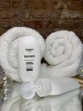 Load image into Gallery viewer, Two white squeeze bottles of hand lotion in front of white towels with a textured background