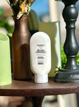 Load image into Gallery viewer, Island Coconut Hand Lotion displayed beside green candles, a brown vase, and black décor.