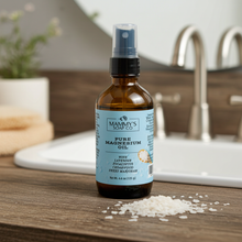 Load image into Gallery viewer, A bottle of Mammy's Soap Co. Pure Magnesium Oil with lavender, rosemary, cedarwood and sweet marjoram, set on a bathroom counter with magnesium flakes in front and a sink in the background.