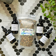 Load image into Gallery viewer, Herbal Supplement tinctures and bag of Alkaline Tea bag laying on a tile surface.