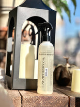 Load image into Gallery viewer, Relax Luxury Body Oil displayed on a wooden table beside a black lantern, candles, and fall décor.