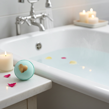 Load image into Gallery viewer, Bathroom scene with a bathtub, candles, flower petals, and a green bath bomb with gold on top.