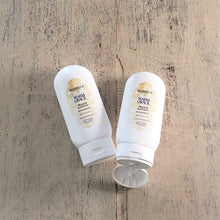 Load image into Gallery viewer, Two white bottles of Warm Grace Hand Lotion on a distressed wood table.
