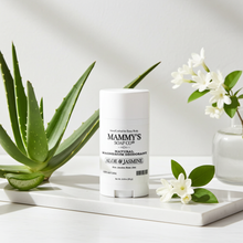 Load image into Gallery viewer, Mammy's Soap Co. deodorant stick on a white surface with aloe vera plant and flowers.
