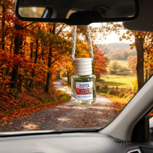 Load image into Gallery viewer, A small clear glass car air freshener bottle with a white cap hangs from a twisted cord in a car windshield. The label reads 'Mammy's Soap Co Apple Maple Bourbon'.
