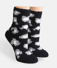Load image into Gallery viewer, A pair of fuzzy black socks with a white cloud-like pattern, displayed on foot-shaped mannequin forms against a light gray background.

