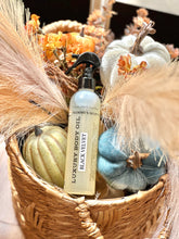 Load image into Gallery viewer, Black Velvet luxury body oil displayed in a fall basket with pumpkins and flowers.

