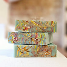 Load image into Gallery viewer, Three bars of green soap with red and yellow swirls with a blurred background
