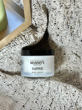 Load image into Gallery viewer, Dapper Body Cream nestled in a soft, cream-colored textured blanket beside a gold tray.
