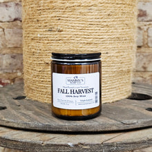 Load image into Gallery viewer, Amber jar of 'Fall Harvest' soy candle from Mammy's Soap Co. on a wooden surface with jute background
