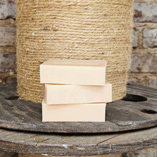Load image into Gallery viewer, Stack of beige soap bars on a wooden surface with a spool of twine in the background.
