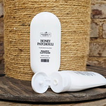 Load image into Gallery viewer, Hand lotion bottle with Mammy's Soap Co 'Honey Patchouli' scent on a wooden surface with jute background
