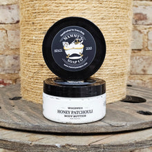 Load image into Gallery viewer, Mammy's Soap Co. whipped honey patchouli body butter on a wooden surface with a jute background
