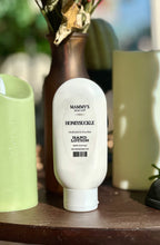 Load image into Gallery viewer, Honeysuckle Hand Lotion displayed on a wooden table beside green candles and a brown vase.
