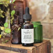 Load image into Gallery viewer, Bottle of Mammy's Soap Co. Joint &amp; Muscle Support on a wooden surface with plants in the background
