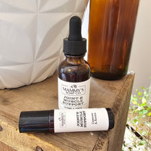 Load image into Gallery viewer, Bottle and roller ball of Mammy's Soap Co. Joint &amp; Muscle Support on a wooden surface.
