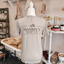 Load image into Gallery viewer, Mannequin wearing a 'Mammy's Soap Co' t-shirt in a soap-making workshop.
