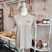 Load image into Gallery viewer, Gray t-shirt on a mannequin in a store setting with products in the background
