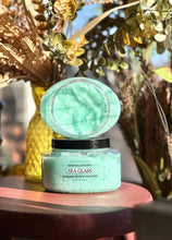 Load image into Gallery viewer, Sea Glass Sugar Body Polish displayed open on a red wooden table surrounded by plants and fall décor.

