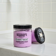 Load image into Gallery viewer, A jar of Mammy's Soap Co. 'Starry Night' foaming body scrub sits on a white marble countertop with a tiled bathroom wall behind it.
