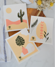 Load image into Gallery viewer, Set of 3 Swedish dishcloths with cactus, plant, and abstract designs on a wooden surface.
