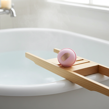Load image into Gallery viewer, Wooden bath caddy with a pink bath bomb on a white bathtub
