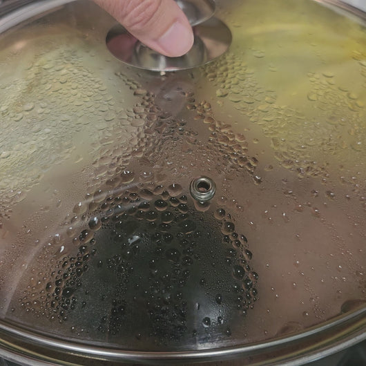 A video of a pot lid being lifted to reveal purple bubbling liquid with two large "satchet" bags.