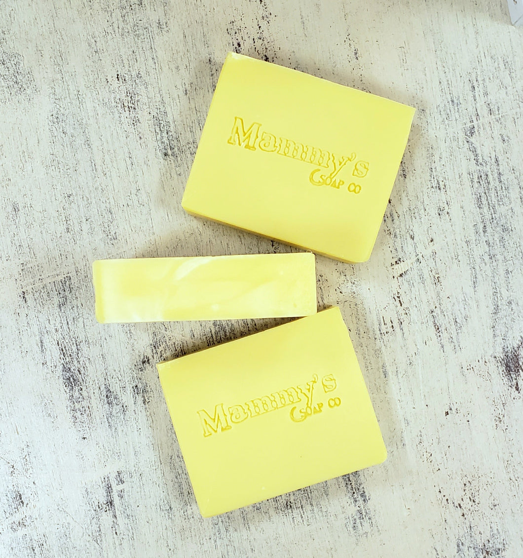 3 yellow bars of soap displayed on a distressed wood surface.