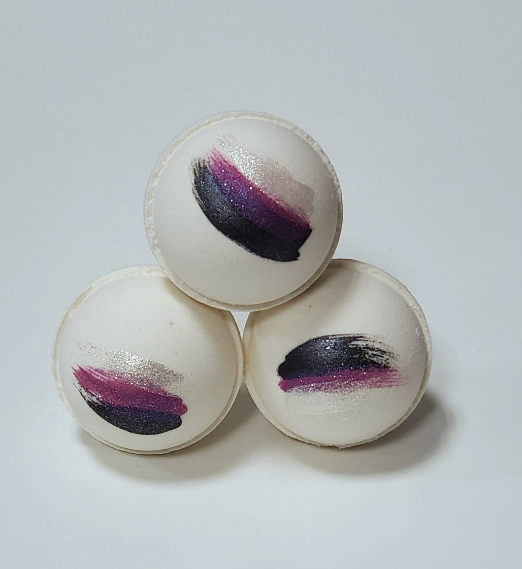 3 white bath bombs with navy, purple & silver stripes stacked in a pyramid
