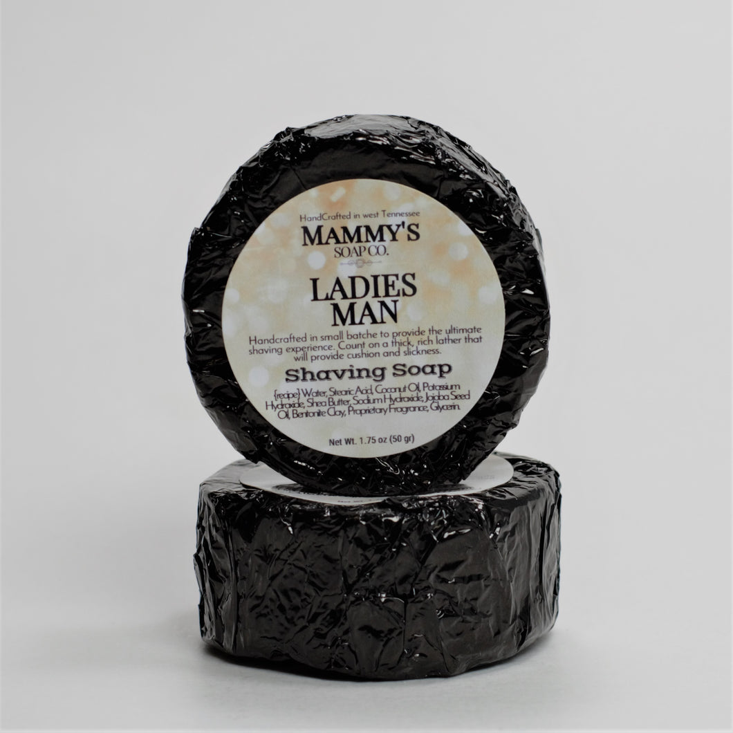 two ladies man stacked handmade shaving soap pucks wrapped in black foil with label