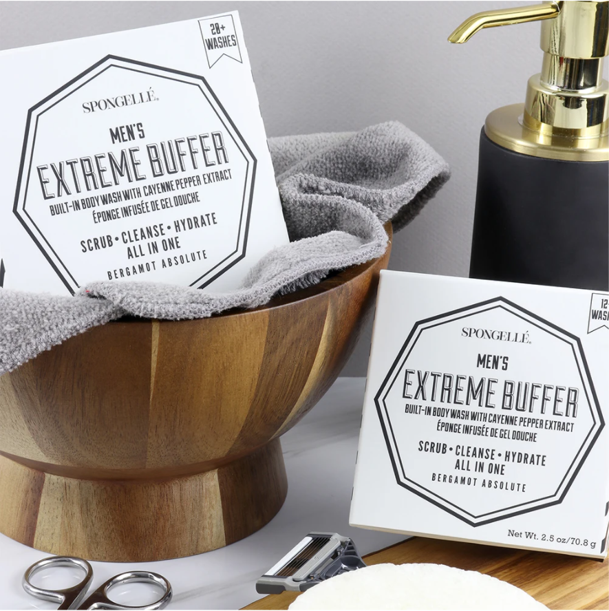 2 white boxes with black lettering, black and gold soap pump, wooden bowl, razor, scissor handles, gray towel