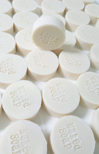 several white round bars of soap stamped Naked Soap