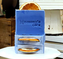 Load image into Gallery viewer, Three bars of blue soap with an orange slice in the top stamped 'Mammy's Soap Co' with wood in the background.
